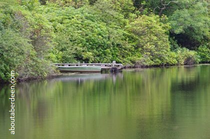 wooden boat moored on jetty by loch